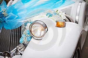 Wedding car with beautiful decorations. Close up white and cyan flowers roses on newlyweds car