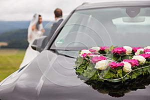 Wedding car with bride and groom in the background