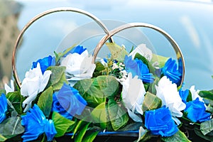 Wedding car decorative with rings and flowers in white and blue colors.
