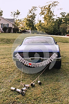 The wedding car with just married sign and cans tied to the trunk