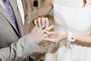 Wedding ceremony. Bride puts on golden wedding ring to groom`s finger closeup. Bride and groom.
