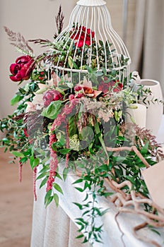 Wedding ceremony decoration in restoraunt. The composition of red and pink peonies, rose flowers, eucalyptus green stands on table