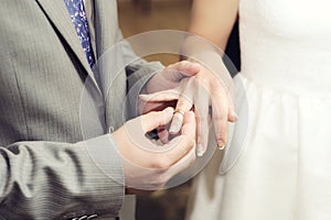 Wedding ceremony. Groom puts on golden wedding ring to bridal`s finger closeup. Bride and groom.