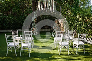 Wedding ceremony with transparent chairs and arch with flowers