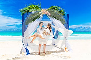 Wedding ceremony on a tropical beach in blue. Happy groom and br