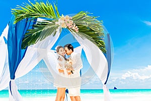 Wedding ceremony on a tropical beach in blue. Happy groom and br