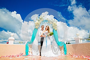 Wedding ceremony on a tropical beach in blue. Happy groom and br