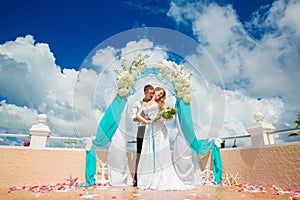 Wedding ceremony on a tropical beach in blue. Happy groom and br