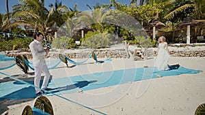 Wedding ceremony on a tropical beach among palm trees and the ocean. The bride comes to him solemnly. Shooting in motion