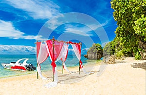 Wedding ceremony on a tropical beach in red. Arch decorated with flowers