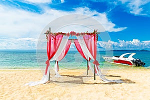 Wedding ceremony on a tropical beach in red. Arch decorated with flowers