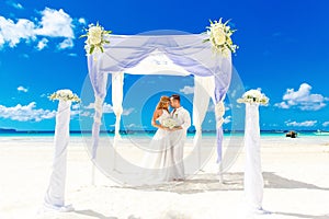 Wedding ceremony on a tropical beach in white. Happy groom and b