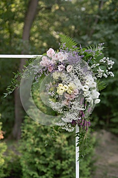 Wedding ceremony. Very beautiful and stylish wedding arch, decorated with various fresh flowers, standing in the garden.