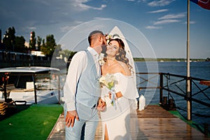 wedding ceremony by water on dock. bride and groom.