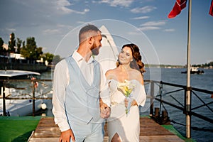 wedding ceremony by water on dock. bride and groom.