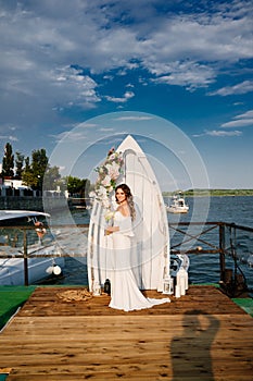 a wedding ceremony by the water on the dock. bride with long curls.