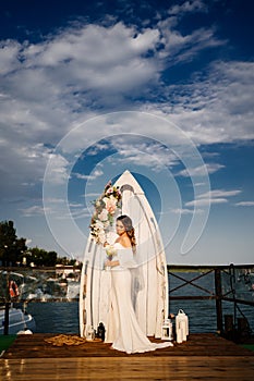 a wedding ceremony by the water on the dock. bride with long curls.