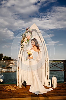 a wedding ceremony by the water on the dock. bride with long curls.