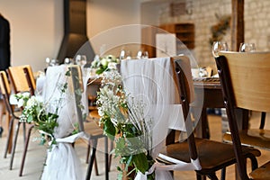 Wedding chairs decorated with white tulle and flowers