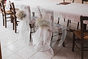 Wedding chairs decorated with white tulle and flowers
