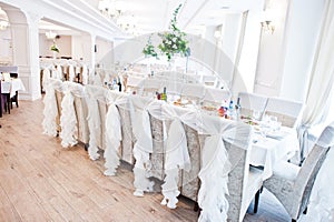 Wedding chairs with white ribbons at reception.