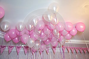 Wedding or children birthday party decoration interior . Helium balloons . Pink and white balloons float on the white ceiling in