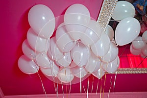 Wedding or children birthday party decoration interior . Helium balloons red float . white balloons float on the white ceiling in