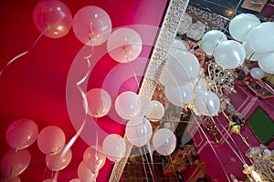 Wedding or children birthday party decoration interior . Helium balloons red float . white balloons float on the white ceiling in