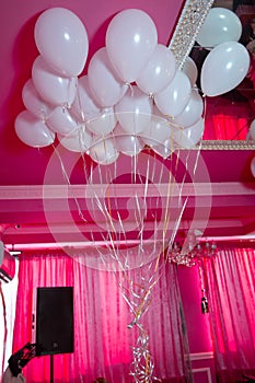 Wedding or children birthday party decoration interior . Helium balloons red float. white balloons float on the white ceiling in