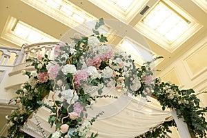 Wedding chuppah decorated with fresh flowers indoor banquet hall of wedding ceremony. Luxury wedding florist decoration artwork