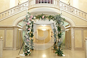 Wedding chuppah decorated with fresh flowers indoor banquet hall of wedding ceremony. Luxury wedding florist decoration artwork