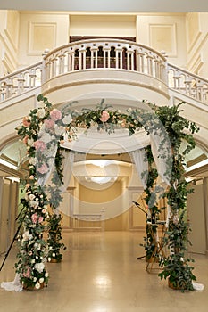 Wedding chuppah decorated with fresh flowers indoor banquet hall of wedding ceremony. Luxury wedding florist decoration artwork