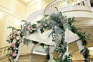 Wedding chuppah decorated with fresh flowers indoor banquet hall of wedding ceremony. Luxury wedding florist decoration artwork