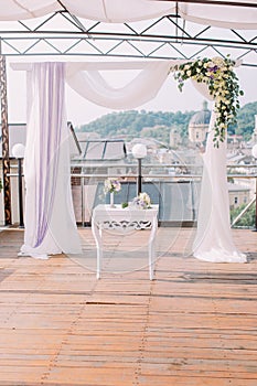 The wedding composition of the little white table and arch decorated with colourful flowers. photo