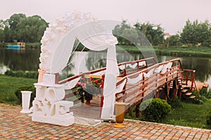 The wedding composition of the signs and arch placed near the wooeden pier.