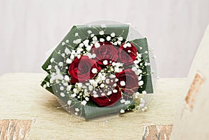 Wedding concept bouquet of red roses and wedding gold rings on light pastel background