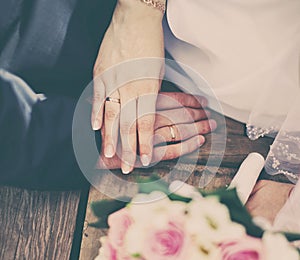 Wedding couple bride and groom holding hands with rings, bouquet of flowers