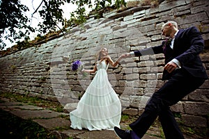 A wedding couple dance behind a stone wall