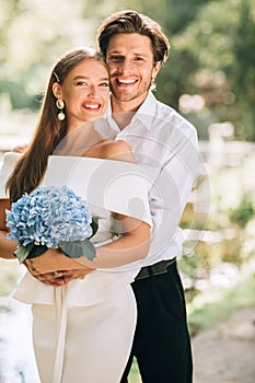 Wedding Couple Embracing Smiling To Camera Posing In Park, Vertical