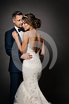 Wedding Couple Fashion Portrait. Bride Back view and Groom embracing Woman. Black Studio Background