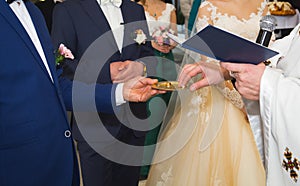 Wedding couple is getting married in the orthodox christian church. Priest is olding golden rings. Traditional ceremony for groom