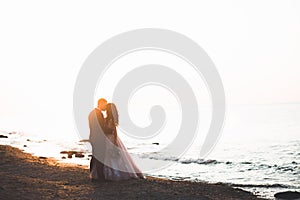 Wedding couple, groom, bride with bouquet posing near sea and blue sky