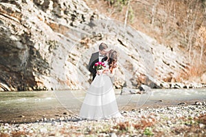 Wedding couple, groom and bride hugging, outdoor near river