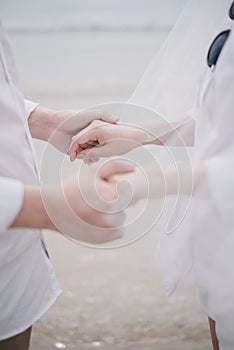 The wedding couple holding each other hand with the beach background, love concept