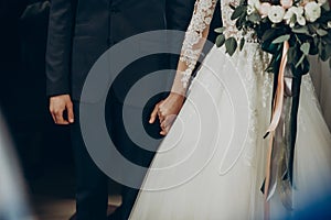 Wedding couple holding hands close up at matrimony wedding ceremony in church. stylish bride and groom hugging. emotional moment,