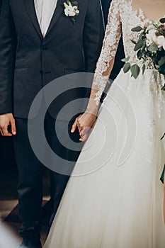 Wedding couple holding hands close up at matrimony wedding ceremony in church. stylish bride and groom hugging. emotional moment,