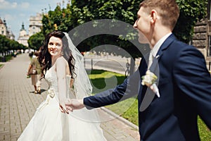 Wedding couple holding hands of each other in park alley