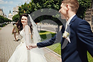 Wedding couple holding hands of each other in park alley photo