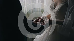 Wedding couple holding hands in front of a window