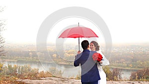 Wedding couple holding red umbrella